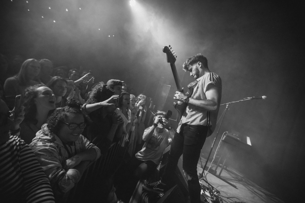 man playing guitar facing fans