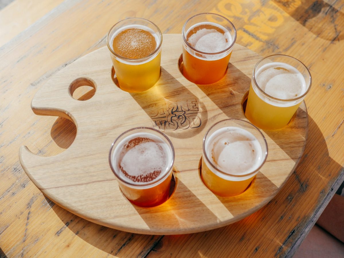 five poured drinking glasses on brown wooden tray